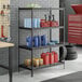 A black metal 4-shelf boltless wire shelving unit with various automotive and cleaning supplies stored on it.
