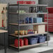 A black heavy-duty five-shelf boltless particle board shelving unit with various storage items placed on the shelves.
