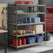 A black heavy-duty five-shelf boltless particle board shelving unit with various storage items placed on the shelves.