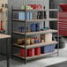 A black heavy-duty five-shelf boltless particle board shelving unit with various storage items placed on the shelves.
