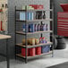 A black heavy-duty five-shelf boltless particle board shelving unit with various automotive and cleaning supplies stored on it.