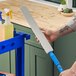 A person using a Lavex 23" flex wand duster to clean a counter.