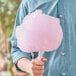 A person holding pink cotton candy spun with Great Western Pink Strawberry Cotton Candy.