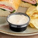 A plate with a sandwich and a Choice plastic souffle cup of dip on it.