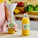 A person pouring orange juice into a clear glass juice bottle.