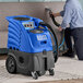 A man using a Lavex carpet extractor with a stainless steel upholstery tool on a couch.