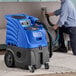 A man using a blue and grey Lavex carpet extractor to clean a couch.