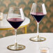 Two Reserve by Libbey Contour wine glasses on a table with a glass of red wine and a candle.