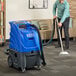 A man using a Lavex heated carpet extractor with hoses on a carpet.