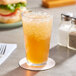 A glass of AriZona Arnold Palmer Lite Half and Half Iced Tea Lemonade on a table with a sandwich.