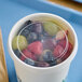 A bowl of fruit in a clear plastic container with a vented lid.