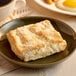 An individually wrapped OMG...It's Gluten Free butter biscuit on a plate with a cup of coffee.