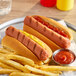 Two Hebrew National beef hot dogs with ketchup and mustard on a plate with fries.