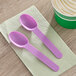 A pair of purple plastic spoons on a napkin.