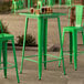 A Lancaster Table & Seating Jade Green Bar Height Outdoor Table with a green chair in an outdoor patio.