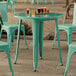 A Lancaster Table & Seating aquamarine outdoor table with chairs on a patio.