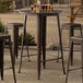 A Lancaster Table & Seating Alloy Series round copper bar height table with several glasses of beer on it.