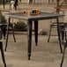 A Lancaster Table & Seating Alloy Series distressed onyx black table with glasses of beer on it.