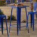 A Lancaster Table & Seating blue metal bar table on an outdoor patio.