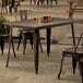 A Lancaster Table & Seating Distressed Copper outdoor table with chairs on a patio.