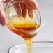 A person pouring Hometown Provisions wildflower honey into a glass bowl.
