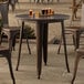 A Lancaster Table & Seating round copper outdoor table with a drink on it.