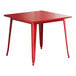 A red square Lancaster Table & Seating outdoor table with metal legs.