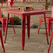 A Lancaster Table & Seating red outdoor table with glasses of beer on it.