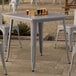 A Lancaster Table & Seating outdoor table and chairs on a patio with glasses of beer on it.