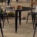 A Lancaster Table & Seating black table and chairs on an outdoor patio.