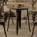 A Lancaster Table & Seating round distressed copper table and chairs on a stone patio.