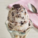 A close up of a scoop of ice cream with oreo cookies on top.