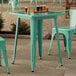 A Lancaster Table & Seating aquamarine table on a concrete patio with chairs and drinks.