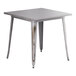 A Lancaster Table & Seating distressed nickel gray metal table with legs and a square top.