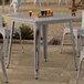 A Lancaster Table & Seating distressed nickel gray outdoor table on a patio with glasses of beer on it.