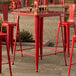 A Lancaster Table & Seating ruby red bar table on an outdoor patio.
