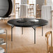 A 72-inch round black heavy-duty blow molded plastic folding table with black legs.