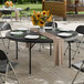 A 72-inch round black heavy-duty blow molded plastic folding table with black legs, set for dining outdoors.