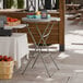 A round gray bar height plastic folding table with gray legs.