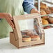 A woman holding an Innopak kraft bakery box of donuts.