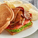 A toasted sandwich with BE Hive plant-based peppered bacon, lettuce, and tomato.