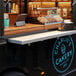 A Regency aluminum folding concession shelf mounted on a wall above a food truck with a sign that says "Charlie's Bakery"