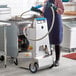 A woman in a blue apron using a Shortening Shuttle machine to transport waste oil.