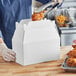 A person holding a Southern Champion white barn box filled with fried chicken.