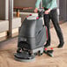 A man using a NaceCare 17" cordless walk behind floor scrubber to clean the floor.