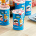 A table with a variety of food items on it including blue containers of Pringles Salt and Vinegar Potato Crisps.