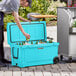A man opening a CaterGator sky blue cooler to put beer and a green bottle inside.