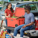 A man and woman sitting on the back of a truck with a CaterGator outdoor cooler.