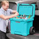 A man opening a CaterGator outdoor cooler and putting bottles inside.