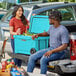 A man and woman sitting on the back of a truck next to a CaterGator sky blue cooler.